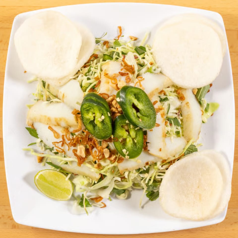 Vietnamese salad with sliced fish, shredded cabbage, herbs, fried shallots, jalapeños, and shrimp crackers.